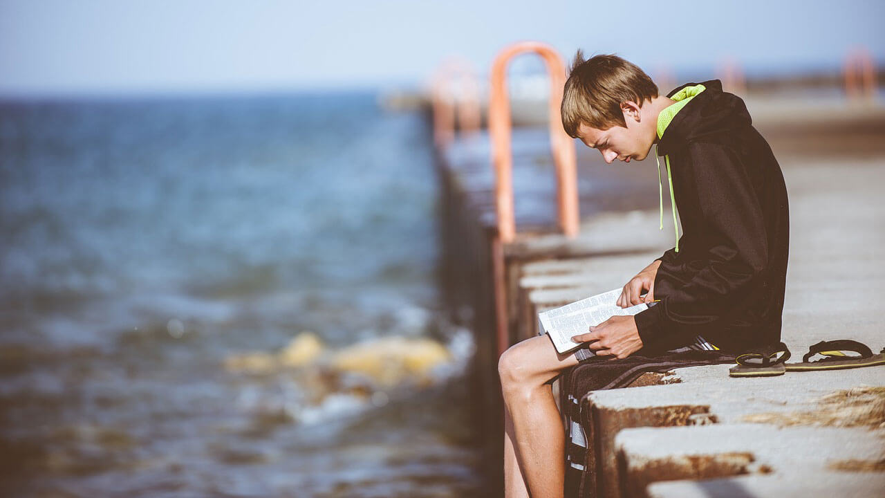 堤防で読書をする男性